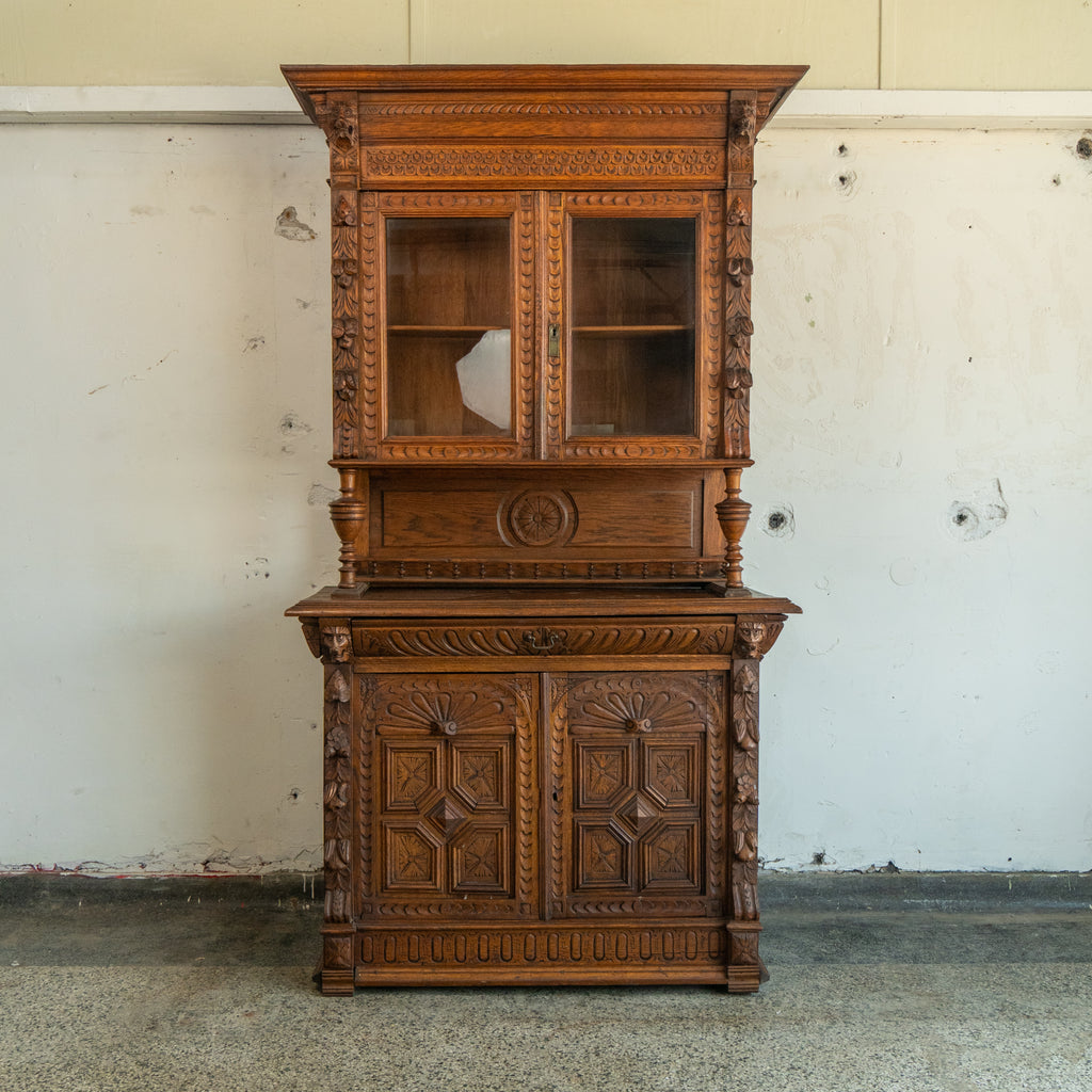 Carved wooden cabinet with glass doors against a plain wall. front view