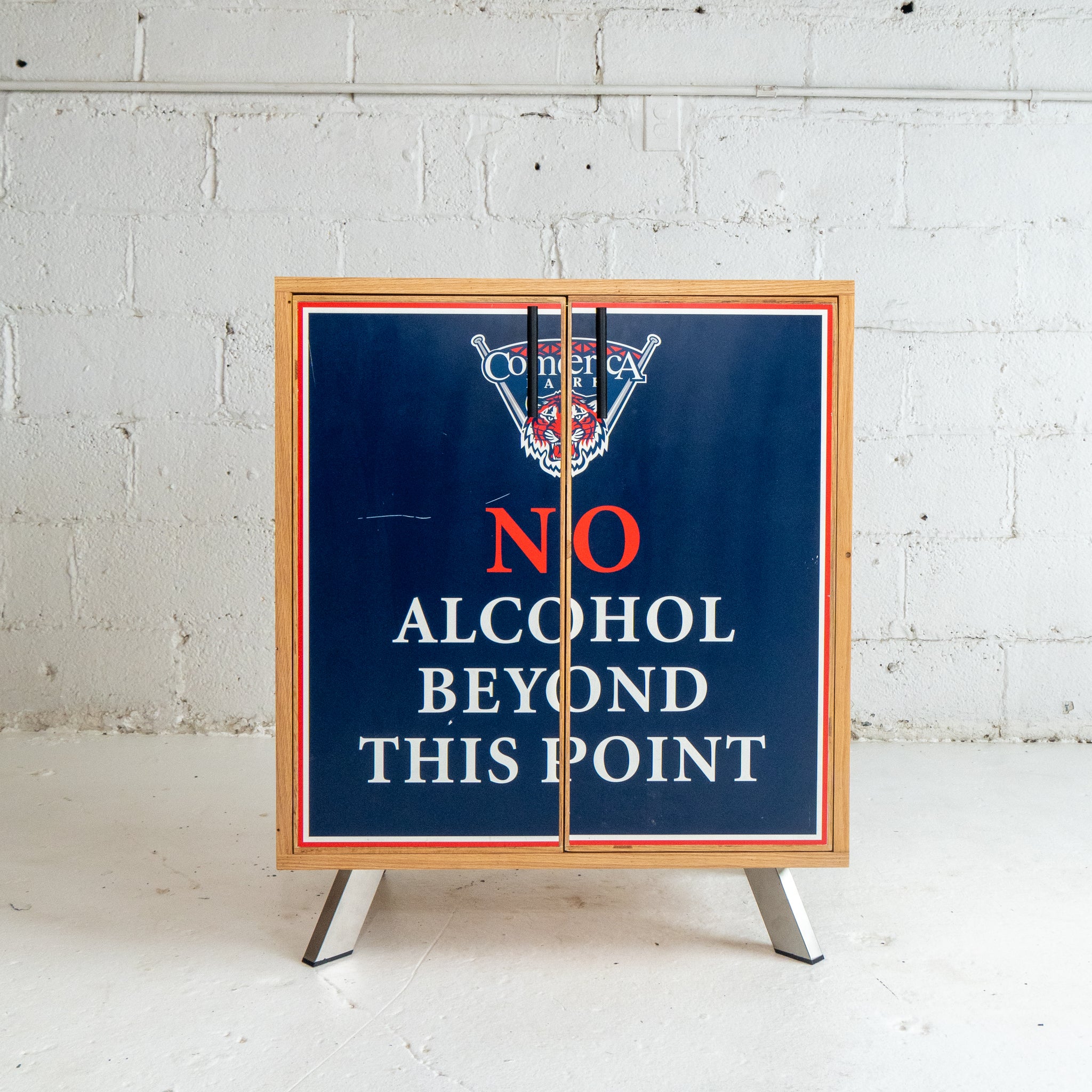 Cabinet with 'No Alcohol Beyond This Point' sign on a white brick wall background