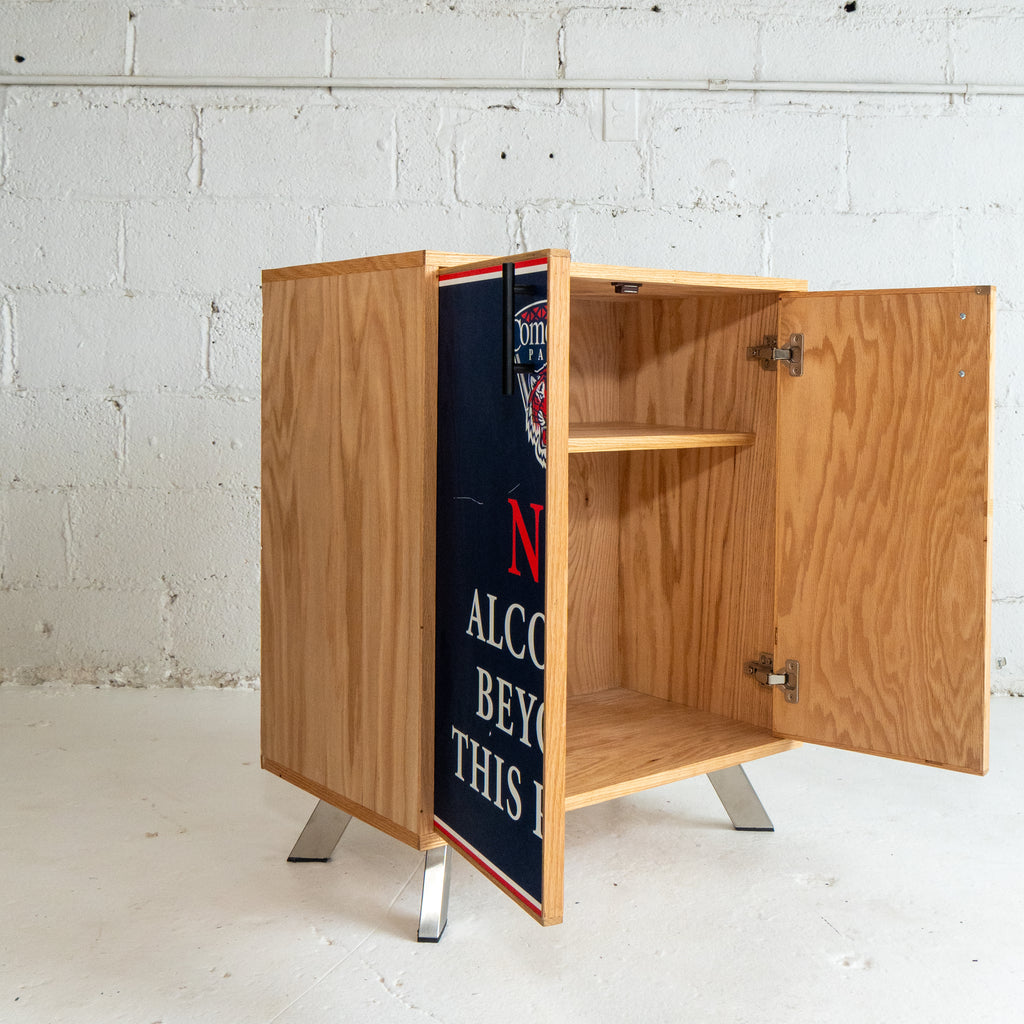 Wooden cabinet with open doors against a white brick wall.