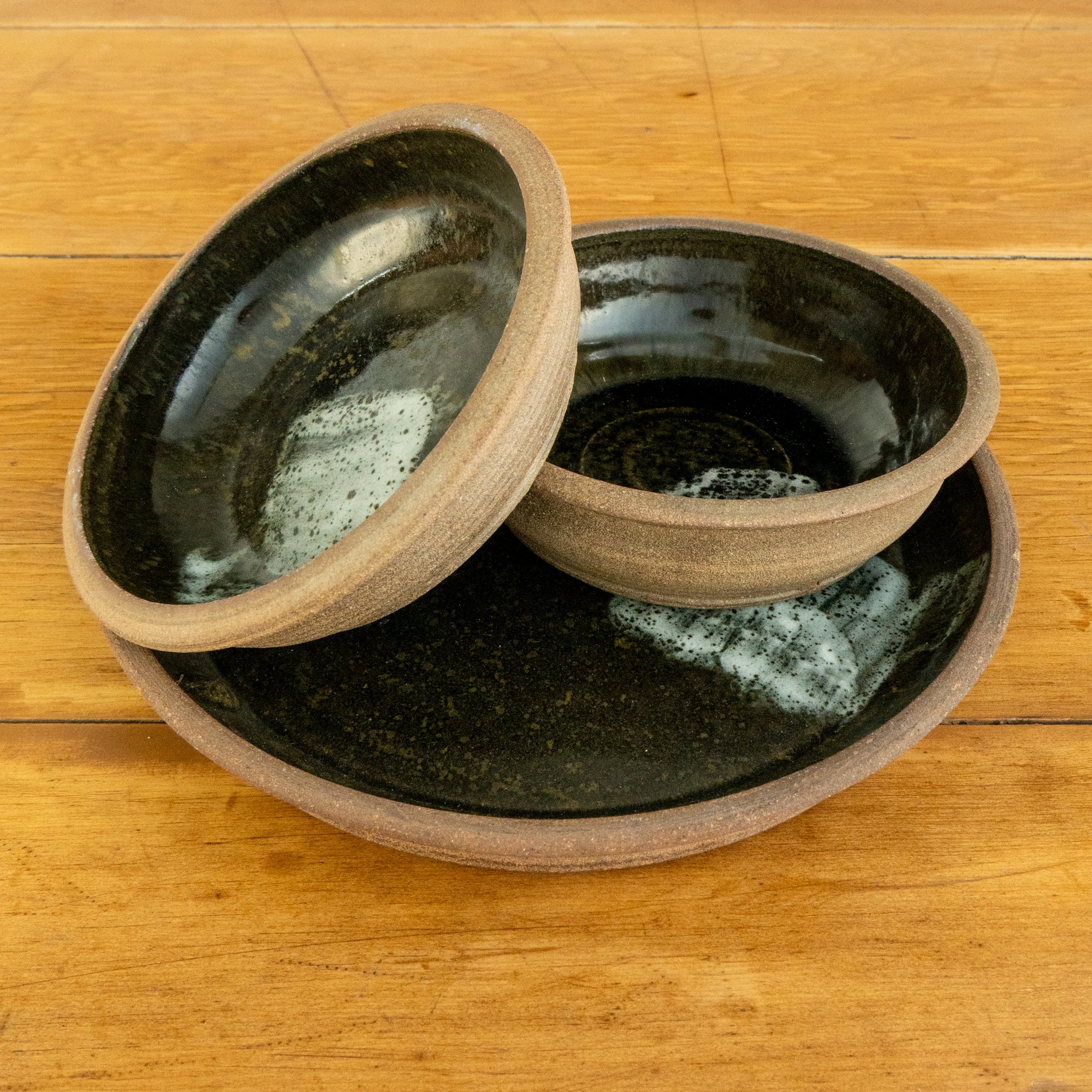 Black stoneware plate with stoneware bowls view